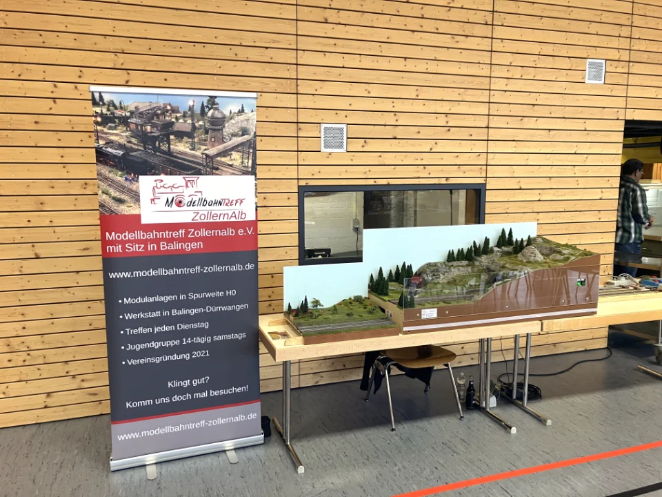 Ansicht des Standes des Modellbahntreffs auf der Spielzeug- und Modelleisenbahnbörse Jungingen (ein H0-Modul, ein Kinder-Modul und Roll-Up-Banner mit Vereinsinfos).